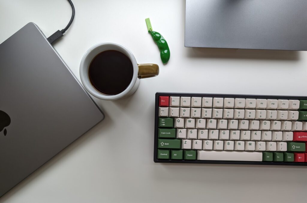 coffee cup on a desk next to a laptop and keyboard